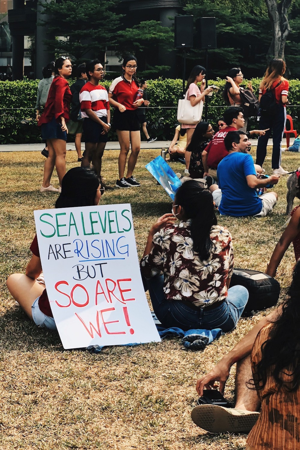 youth demonstrate with a sign saying "sea levels are rising but so are we!"